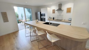 A modern kitchen with a central island, stainless steel appliances, and a view to an outdoor area.