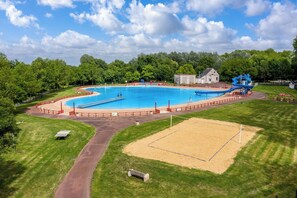 Ein großer Pool mit Rutsche, umgeben von einem eingezäunten Bereich, und ein kleines Gebäude im Hintergrund.