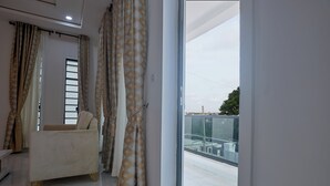 A modern living room with a sofa, curtains, and a balcony view. - Javes Luxury Residences (Lagos)