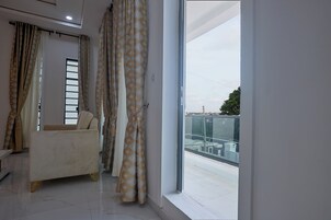 Uma sala de estar moderna com sofá, cortinas e vista para uma varanda.