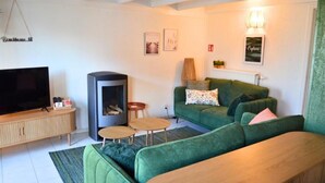 Una sala de estar moderna con un sofá verde, un televisor de pantalla plana, una chimenea y una pequeña mesa de centro.