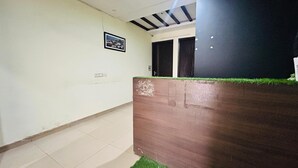 A hallway with a tiled floor, a framed picture on the wall, and a wooden bench with a grassy top. - Corporate Stayz (Gurugram)