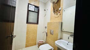 A small bathroom with a toilet, sink, and shower. - Corporate Stayz (Gurugram)