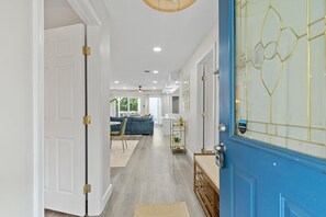Un pasillo con una puerta azul, paredes blancas y suelo de madera.