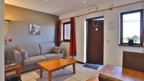Uma sala de estar com um sofá, uma mesa de centro de madeira e uma janela com cortinas.