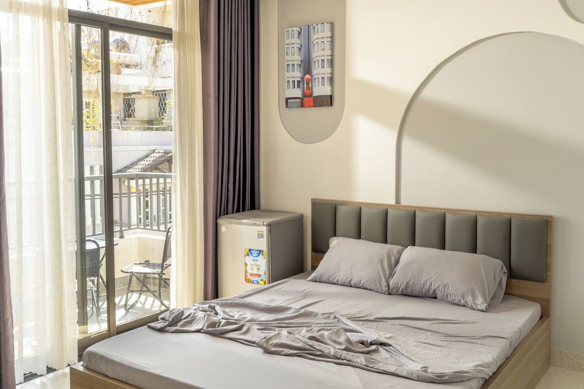 Une chambre moderne avec un cadre de lit en bois, une petite table de chevet et une vue sur le balcon extérieur.
