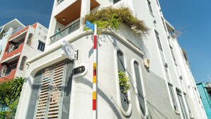 Un edificio de varios pisos con balcones, una puerta visible y una señal de calle.