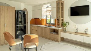 Una cocina moderna con refrigerador empotrado, un comedor con dos sillas y un televisor montado en la pared.