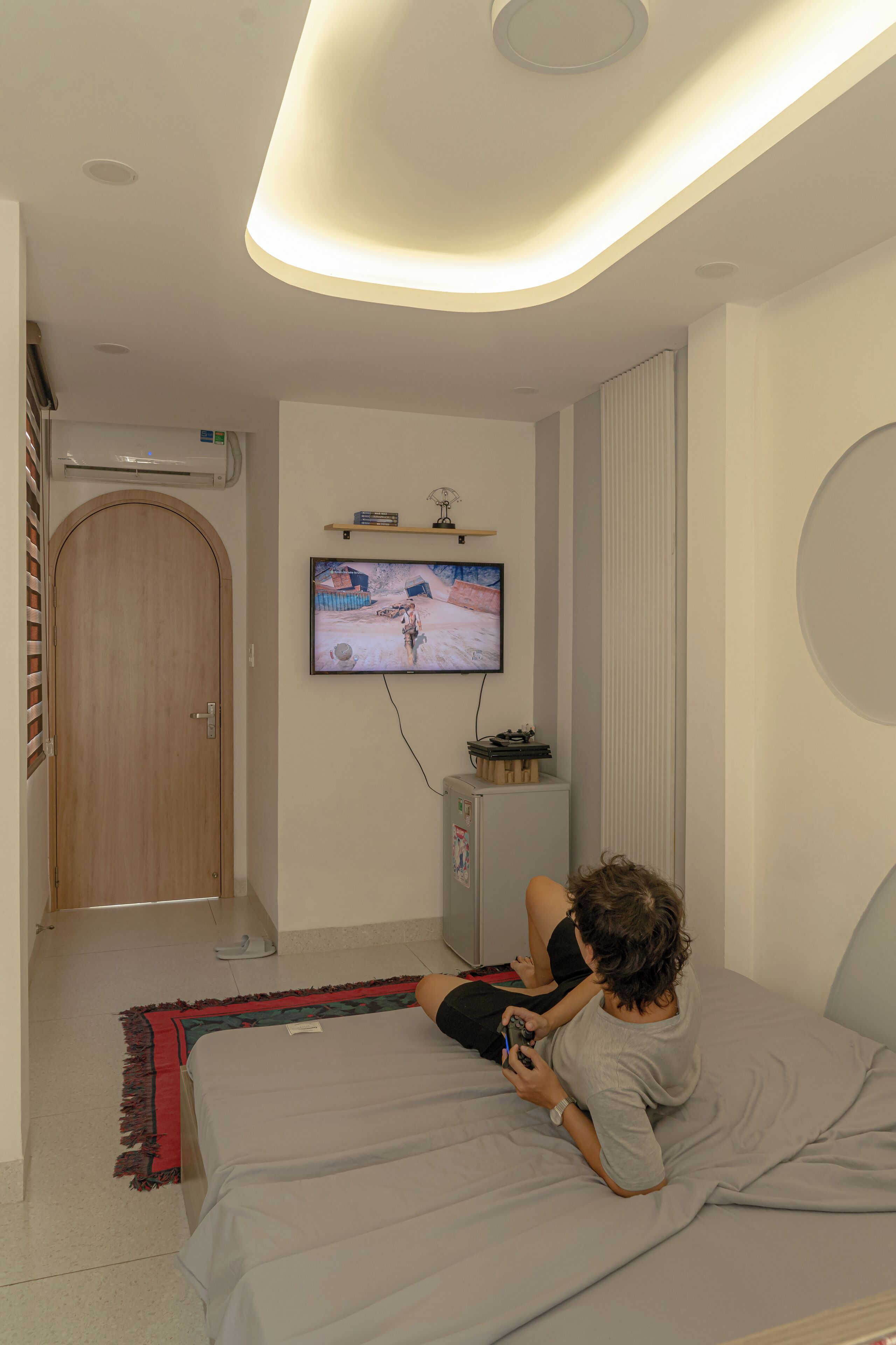 Un dormitorio con una cama, un televisor montado en la pared y una puerta de madera.