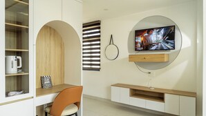 Una sala de estar moderna con una televisión montada en la pared, una mesa de centro de madera, una silla y estanterías empotradas.
