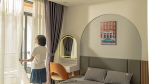 Un dormitorio moderno con cama, escritorio y ventana con cortinas.