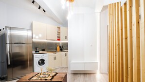 A modern kitchen with stainless steel appliances, a washing machine, and a wooden dining table. - Hidden History - Modern Split-Level (Tbilisi)