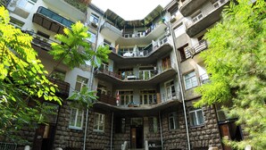 A multi-story building with balconies, a central staircase, and a stone facade. - Hidden History - Modern Split-Level (Tbilisi)