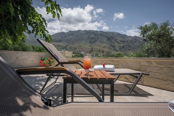 A terrace with a table, chairs, and a drink.