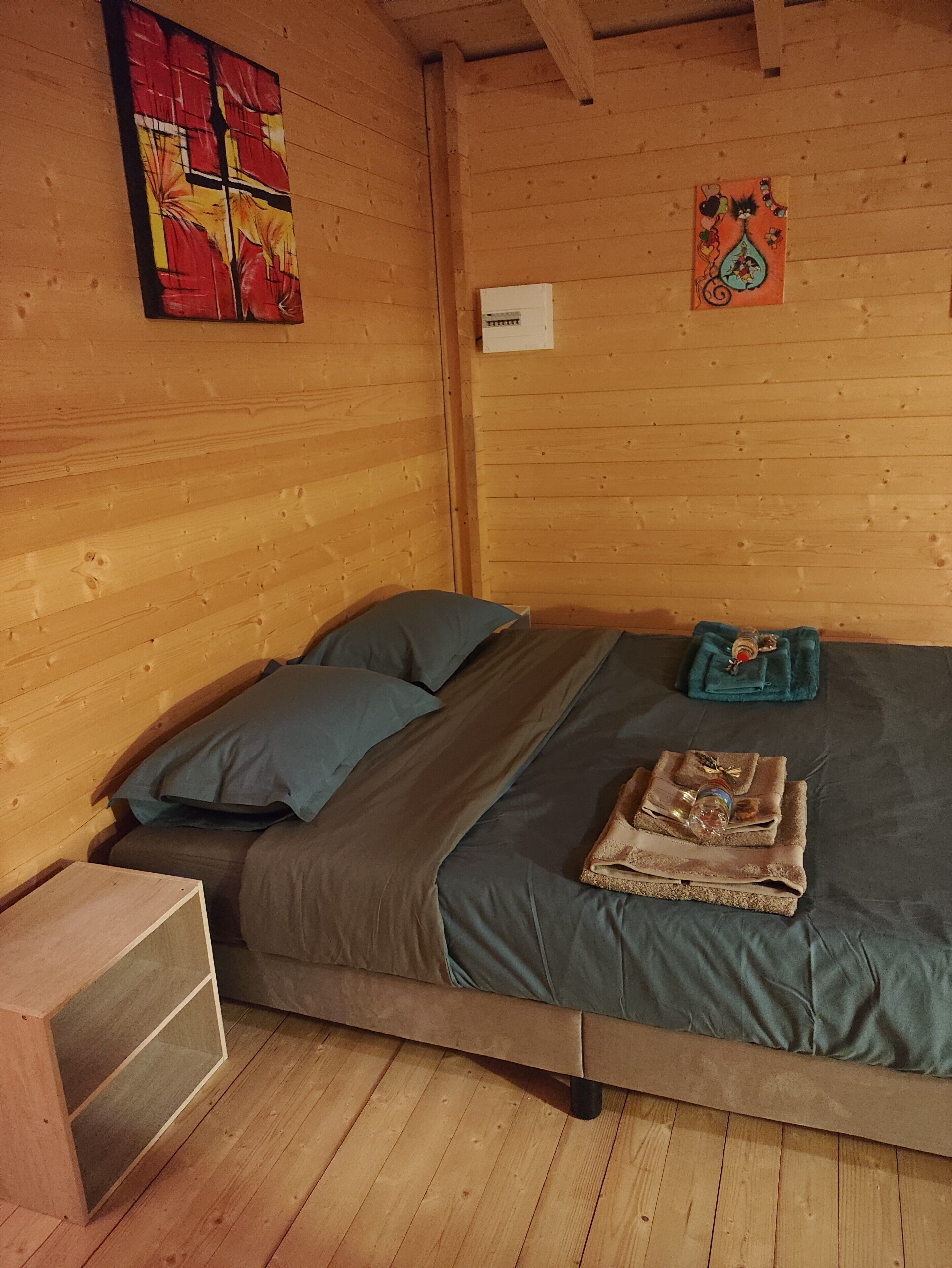 A wooden cabin-style room with a bed, pillows, and a small wooden cabinet.