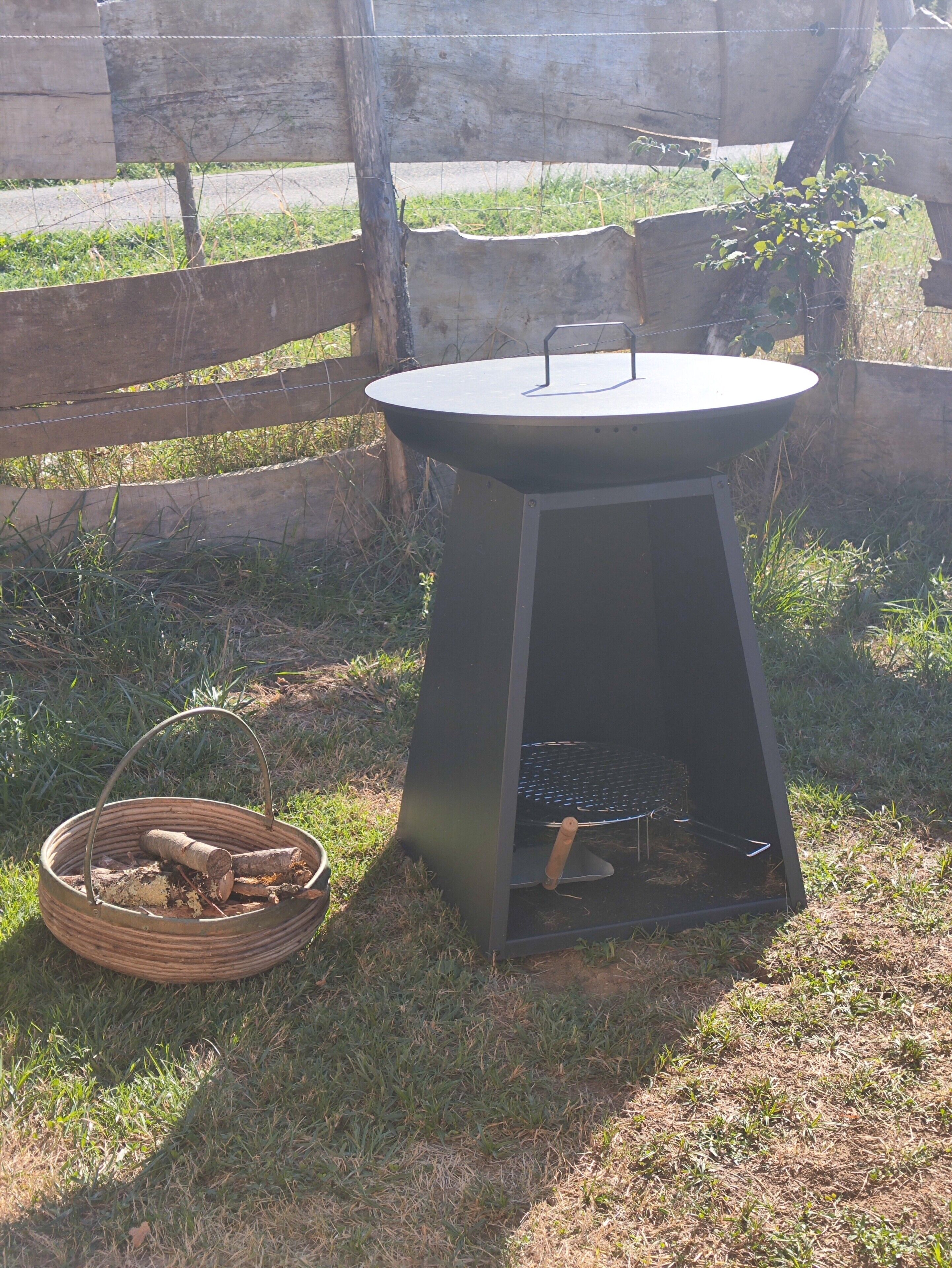 Een buitenbarbecue met een metalen frame, een rond kookoppervlak en een schoorsteen.