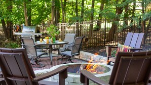 An outdoor patio with a fire pit, seating area, and a grill. - Tree Covered Cottage - Walk to Douglas Beach! (Douglas)