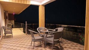 A balcony with wicker furniture, a checkered floor, and a night sky view. - The Hoften Snowia Luxury Stay Near Bhalugarh Waterfall (Dhari)