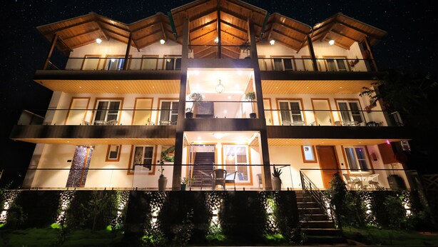A multi-story building with a balcony on the upper floor, a staircase leading to the entrance, and a well-lit entrance area. - The Hoften Snowia Luxury Stay Near Bhalugarh Waterfall (Dhari)
