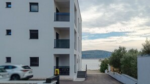 A modern building with multiple balconies overlooking a body of water and a distant hill. - Beautiful apartment in Seline with WiFi (Seline)