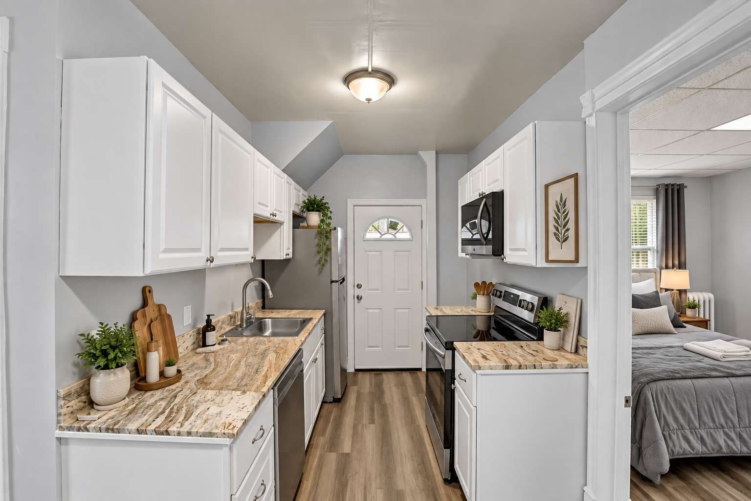 A compact kitchen with white cabinets, a marble countertop, and a central island.