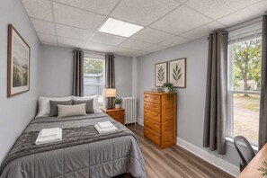 A bedroom with a bed, a dresser, a nightstand, and a window with curtains. - Division Champs 2 - All Star Baseball Rentals (Oneonta)