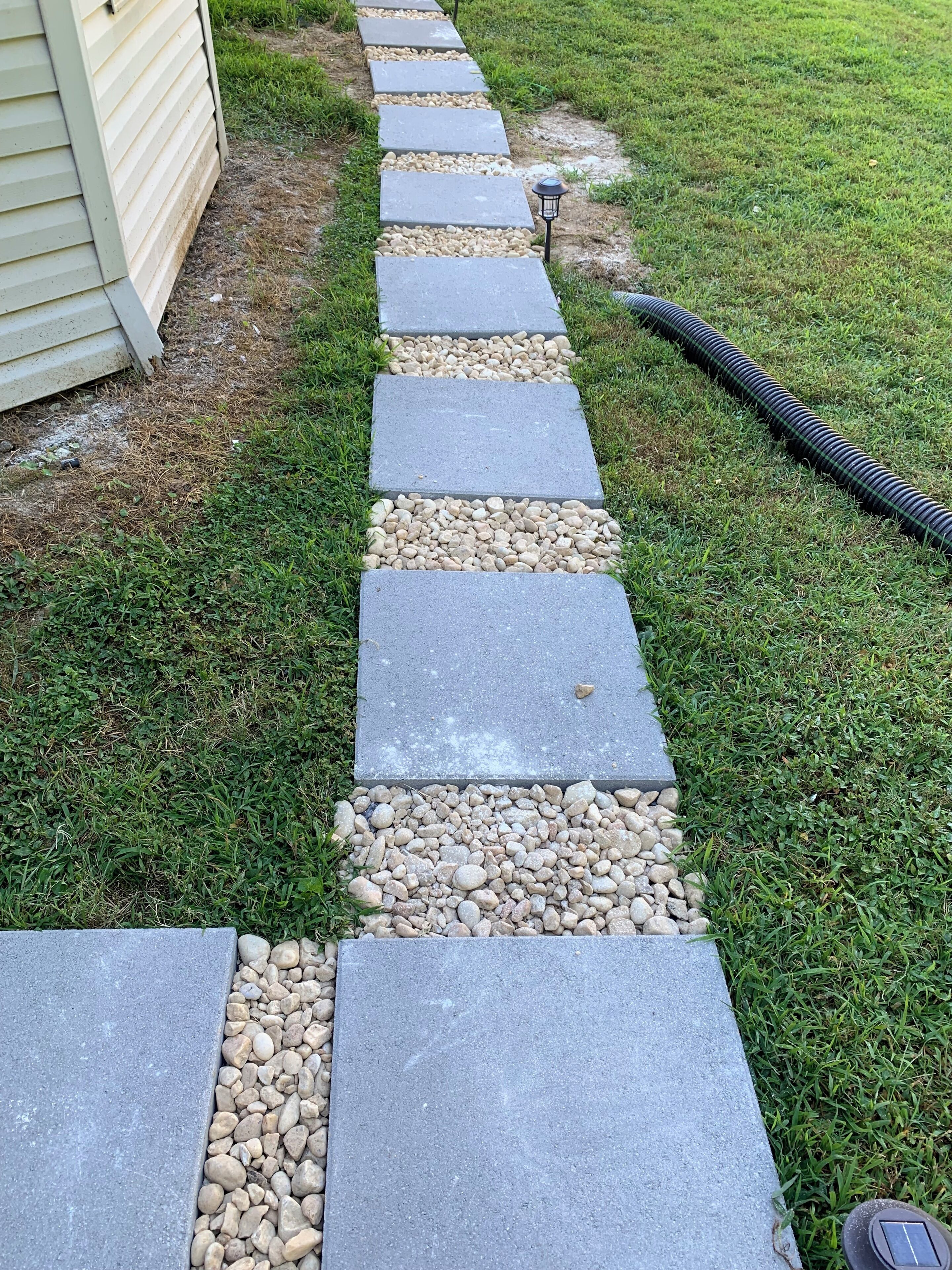 A stone pathway with pebbles leading to a house.