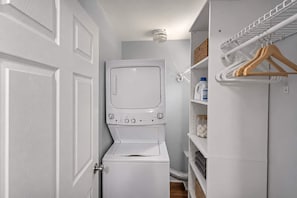 A laundry room with a white washing machine, a drying rack, and shelves with various items. - Main Lineup Apt 3 - All Star Baseball Rentals (Oneonta)