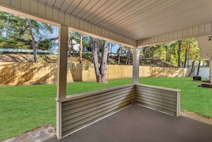 A covered outdoor seating area with a wooden deck and a view of a well-maintained lawn and trees. - Main Lineup Apt 3 - All Star Baseball Rentals (Oneonta)