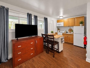 A compact kitchen with wooden cabinets, a microwave, a stove, and a refrigerator. - Main Lineup Apt 3 - All Star Baseball Rentals (Oneonta)