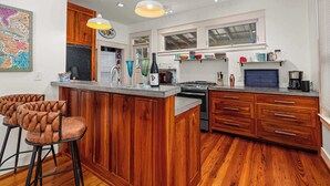 Une cuisine avec des meubles de rangement en bois, un îlot central, des tabourets de bar et divers appareils électroménagers.