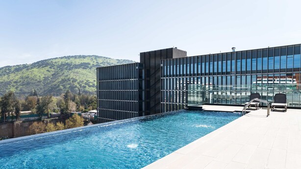Ein modernes Hotel mit einem Dachpool im Infinity-Stil mit Blick auf eine hügelige Landschaft.