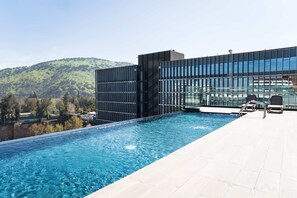 A modern hotel with a rooftop infinity pool overlooking a hilly landscape. - Prime 1BR Flat in Las Condes with Private Parking (Las Condes)