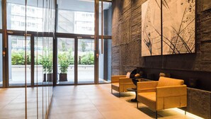 Eine Lobby mit einer Rezeption, zwei Sofas, einem großen abstrakten Gemälde und Blick ins Freie durch Glastüren.