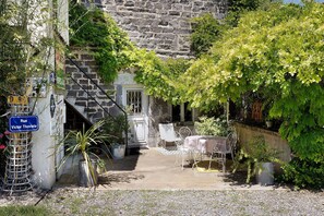 A stone building with a staircase, a metal chair, a table, and potted plants. - Bed and Breakfast 'Terracota' with Shared Terrace, Shared Garden and Wi-Fi (Riom)