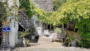 A stone building with a staircase, a metal chair, a table, and potted plants. - Bed and Breakfast 'Pampa' with Shared Terrace, Shared Garden and Wi-Fi (Riom)