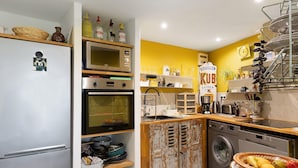 A compact kitchen with a refrigerator, oven, microwave, and washing machine. - Bed and Breakfast 'Pampa' with Shared Terrace, Shared Garden and Wi-Fi (Riom)