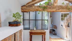 A room with a rustic wooden beam ceiling, a wooden table, a potted plant, and a window with a view. - Bed and Breakfast 'Pampa' with Shared Terrace, Shared Garden and Wi-Fi (Riom)