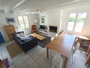 Ein Wohnzimmer mit einer Couch, einem Esstisch, einem Fernseher und einem Kamin.