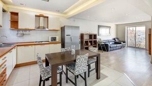 A modern kitchen with a dining area, built-in cabinets, and a large window offering a city view.