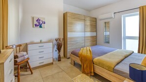 Quarto moderno com cama, cômoda, cadeira, pintura e janela.