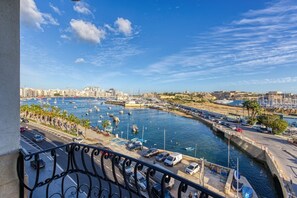 A marina with boats docked, a clear sky, and a cityscape in the background. - Seaview Comfort Apartment Gzira (Il-Gżira)