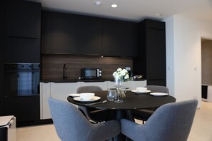 A modern kitchen with dark cabinetry, a black dining table, and grey chairs. - The Mercury Suite with pool (San Ġiljan)