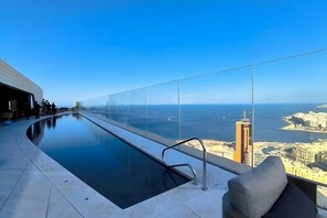 A rooftop pool with a glass railing overlooking a cityscape and the sea. - The Mercury Suite with pool (San Ġiljan)