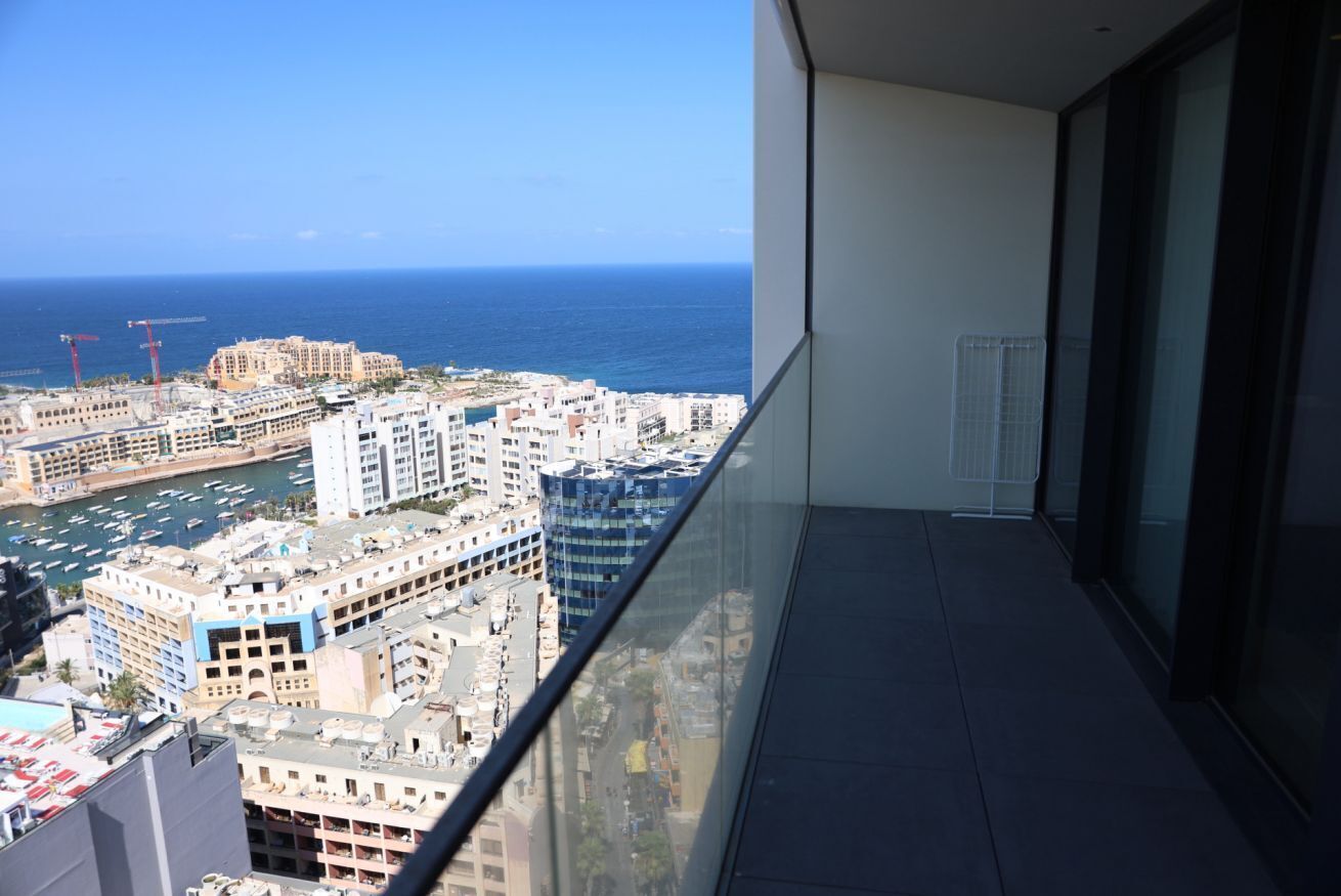 Een balkon met uitzicht op zee en gebouwen.