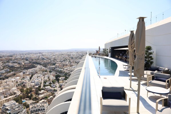 A rooftop pool with a city view, lounge chairs, and umbrellas. - The Mercury Suite with pool (San Ġiljan)