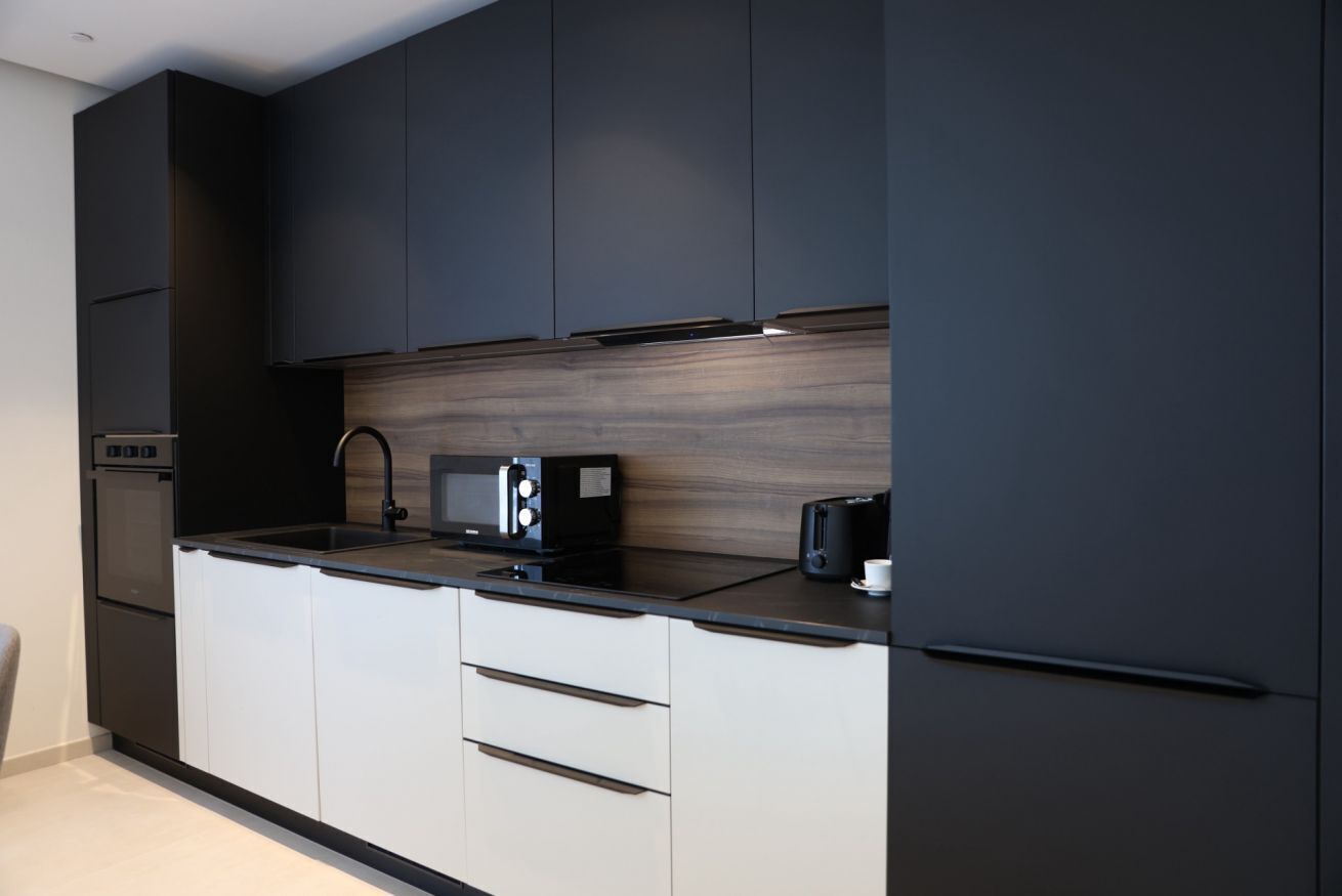 Une cuisine moderne avec des meubles de couleur sombre, un pare-feu en bois et des appareils électroménagers en acier inoxydable.