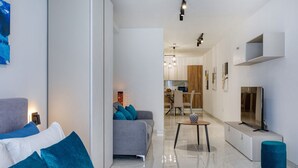 A modern living room with a sofa, a dining area, and a kitchen in the background.