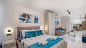 A modern hotel room with a large bed, a sofa, and a dining area.
