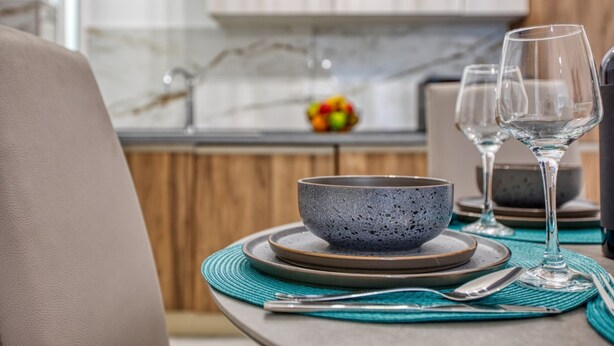 A dining area with a table set for two, featuring a bowl and wine glasses.